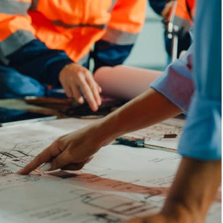 Closeup of team of industrial engineers meeting analyze machinery blueprints consult project on table in manufacturing factory. Working in manufacturing plant or production plant concept.